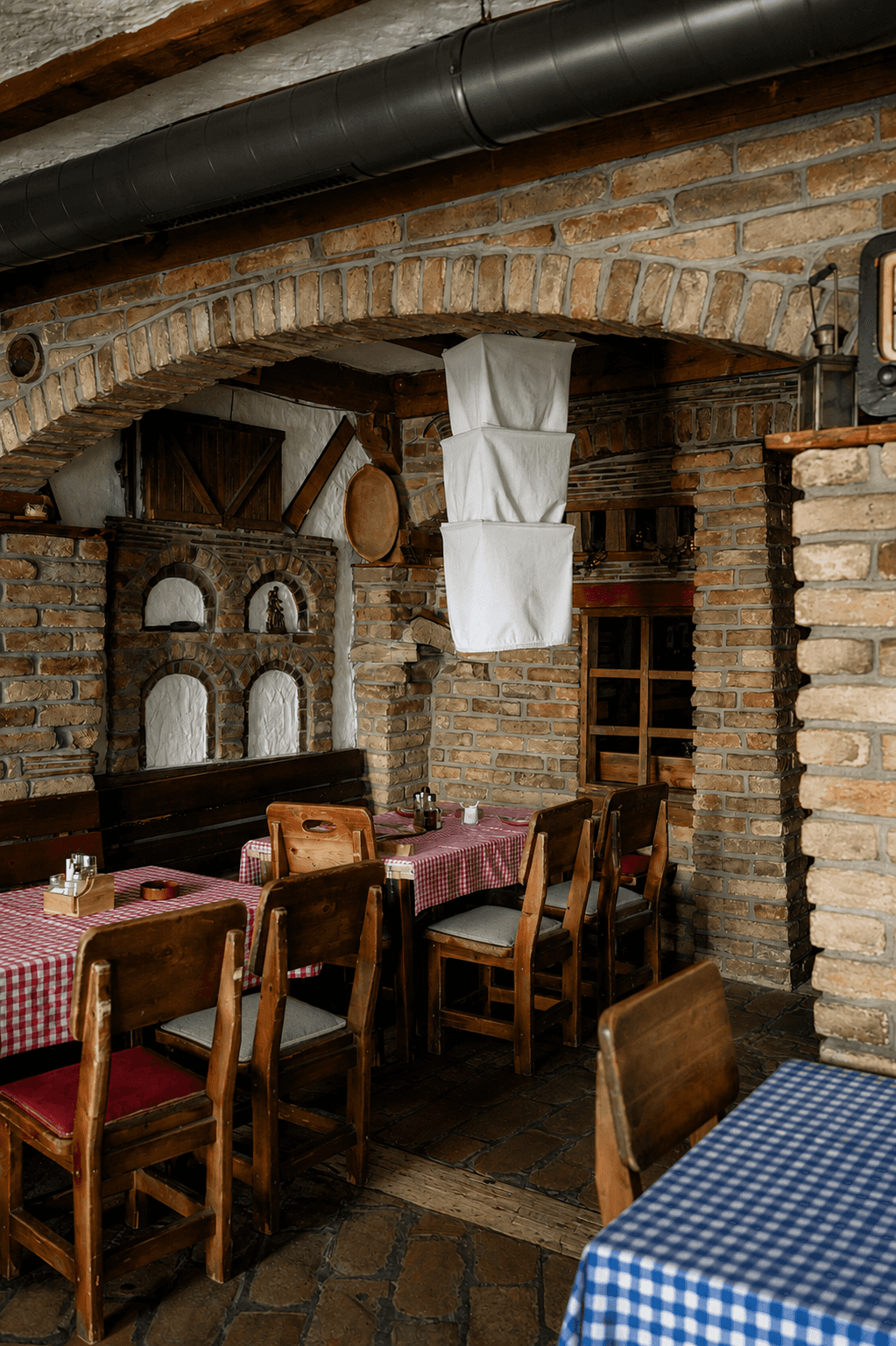 Unutrašnjost etno restorana sa kamenim zidovima i drvenim gredama