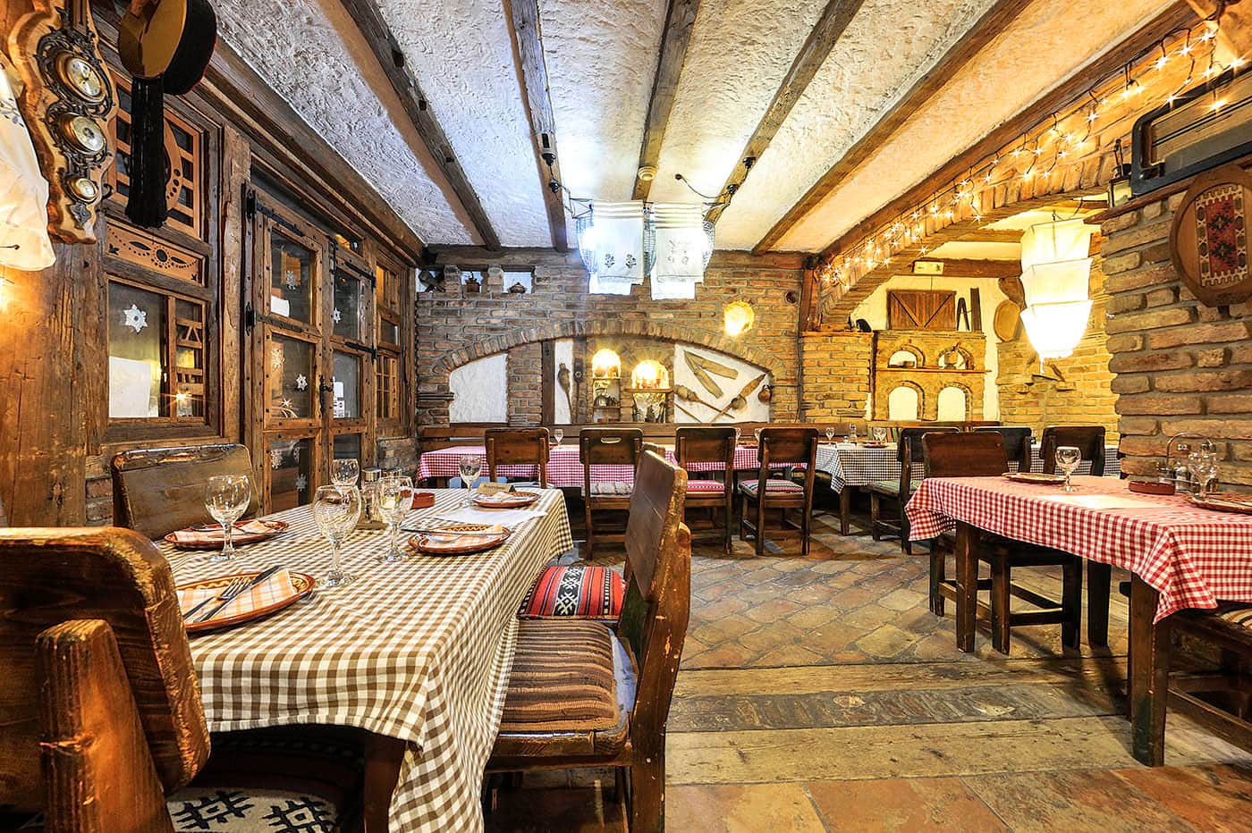 Etno restoran Sučević — kameni zidovi, drvene grede i stolovi sa kariranim stolnjacima